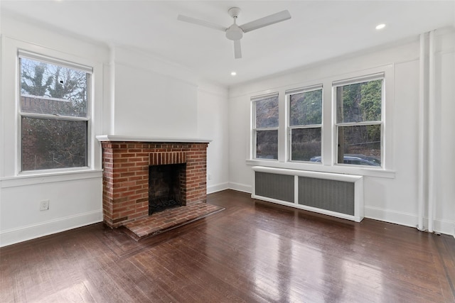 unfurnished living room featuring baseboards, a brick fireplace, wood finished floors, and radiator heating unit