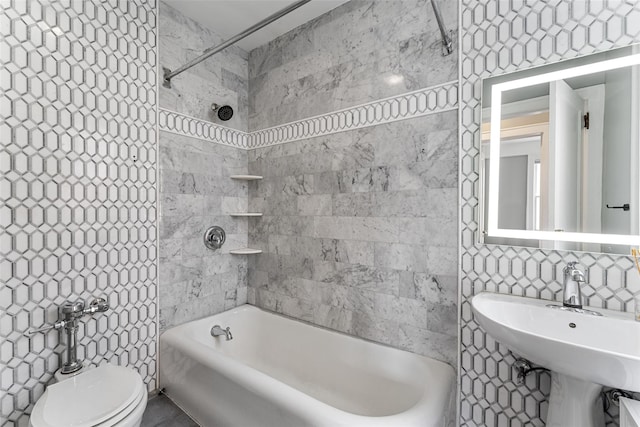 bathroom featuring  shower combination, toilet, tile walls, and a sink