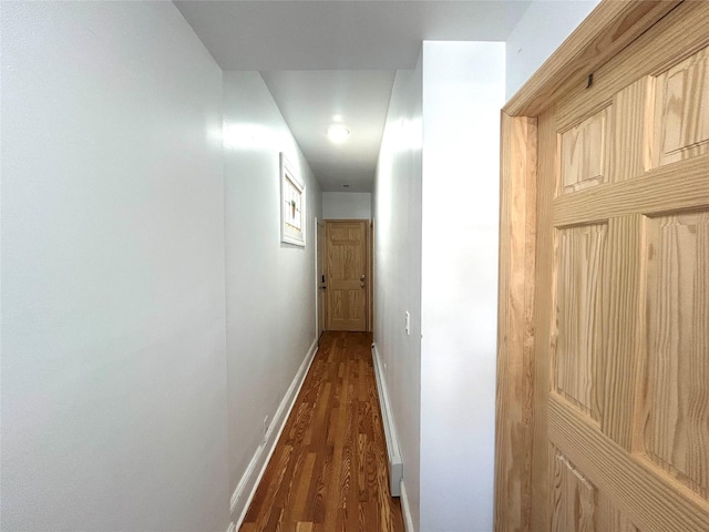 corridor featuring baseboards and dark wood-type flooring