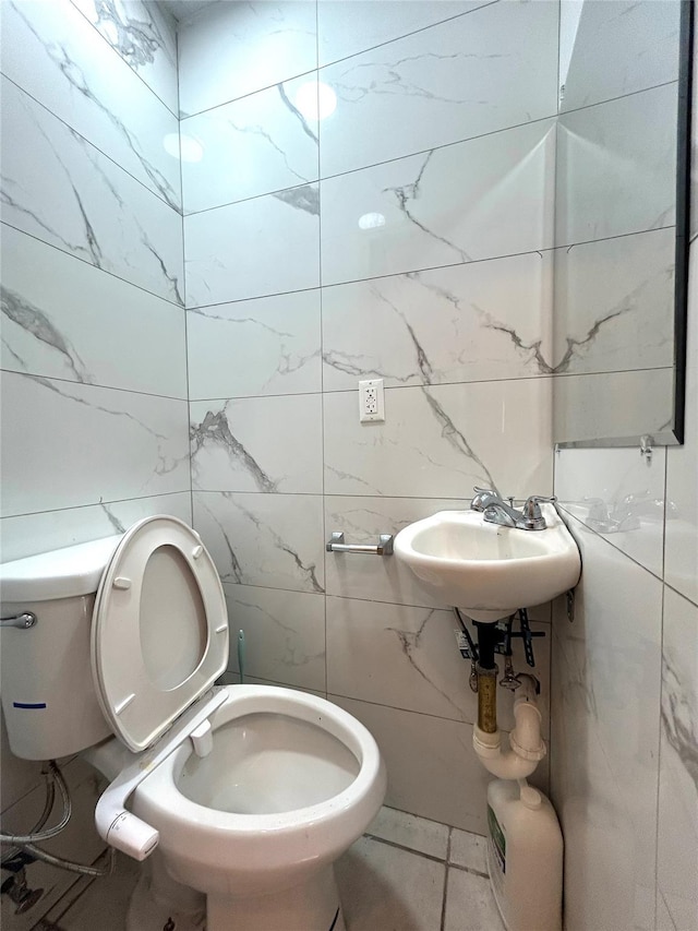 half bath with a sink, toilet, and tile walls