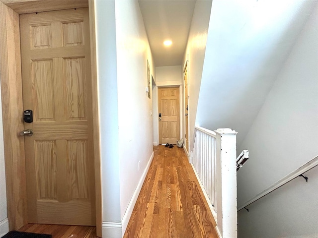 hall featuring an upstairs landing, light wood-style floors, and baseboards