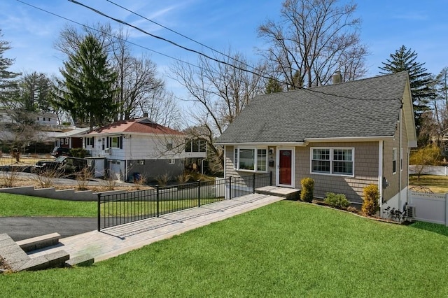 view of front of house featuring fence private yard, roof with shingles, and a front lawn