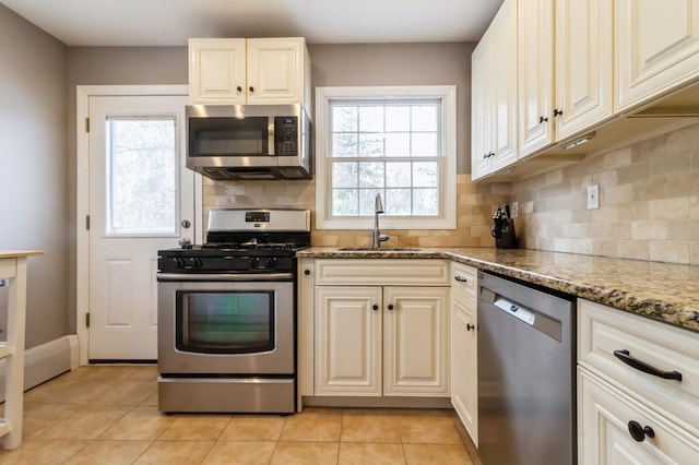 kitchen featuring a sink, appliances with stainless steel finishes, light tile patterned floors, and backsplash