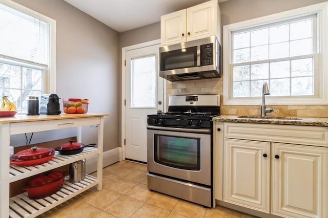 kitchen with a sink, tasteful backsplash, light tile patterned flooring, and stainless steel appliances