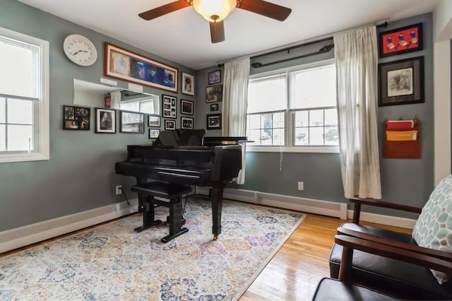 living area featuring baseboards, a ceiling fan, a baseboard radiator, and wood finished floors