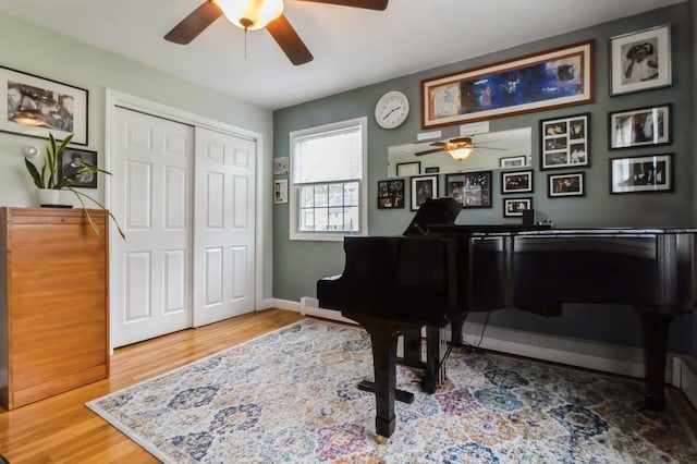 living area with a ceiling fan, baseboards, and wood finished floors