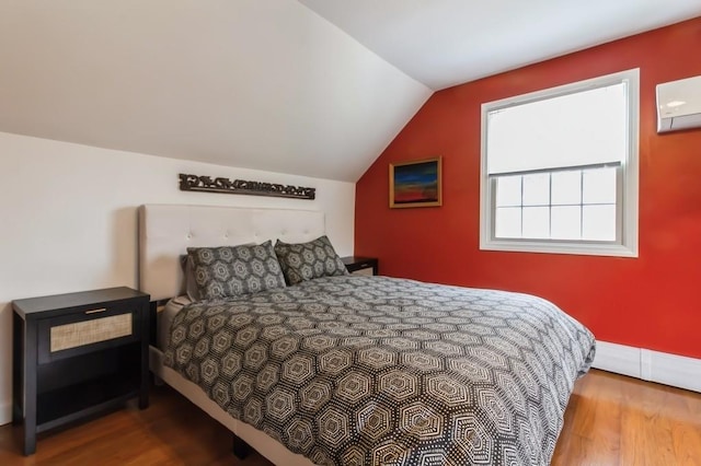 bedroom featuring a wall mounted AC, lofted ceiling, and wood finished floors