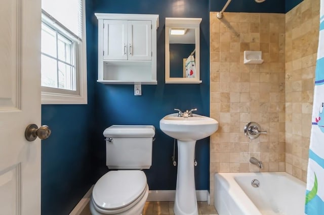 bathroom with baseboards, shower / bath combo with shower curtain, and toilet