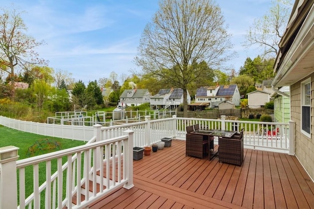 wooden terrace featuring a yard, a residential view, a fenced backyard, and outdoor dining space