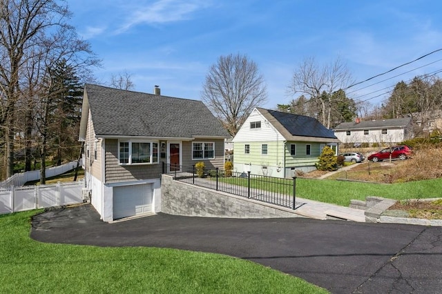 view of front of house with driveway, a garage, fence, a front lawn, and a shingled roof