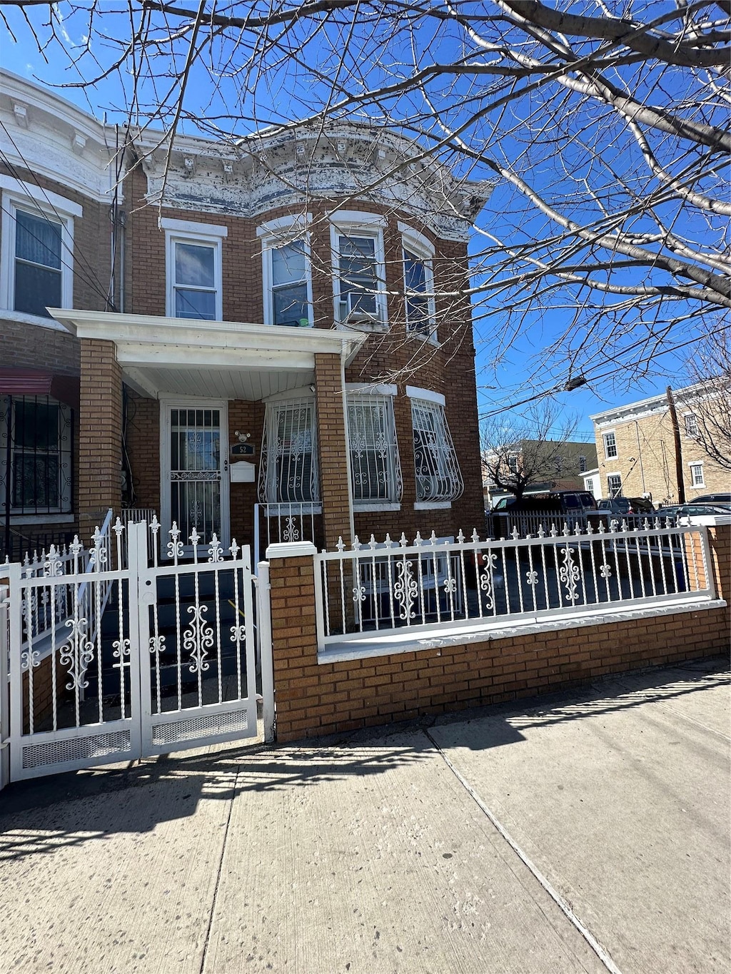 view of front of house featuring a porch, a gate, brick siding, and a fenced front yard