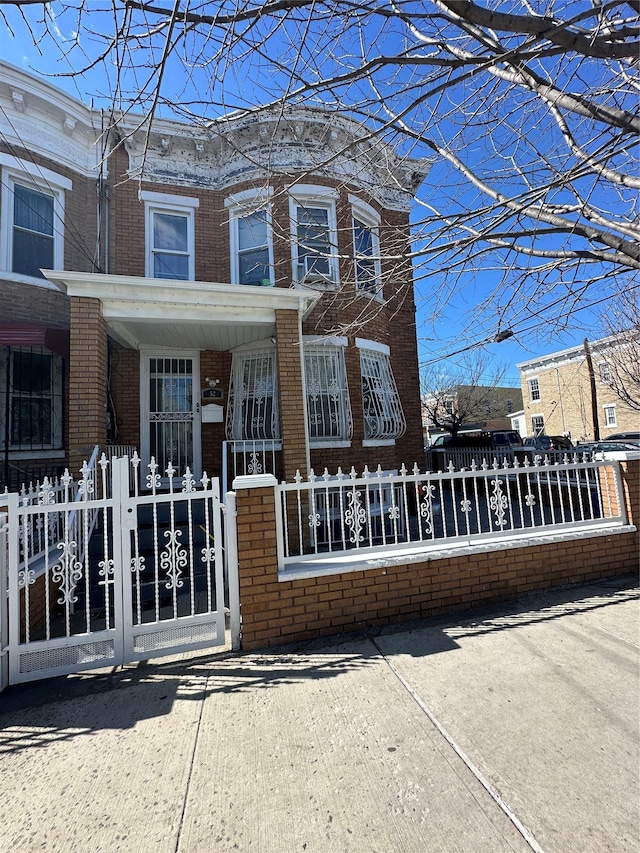 view of front of house featuring a porch, a gate, brick siding, and a fenced front yard