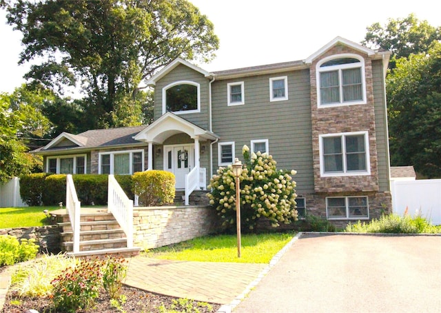 view of front of home featuring stone siding and fence