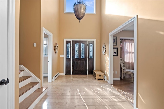 foyer with baseboard heating, a towering ceiling, and a wealth of natural light