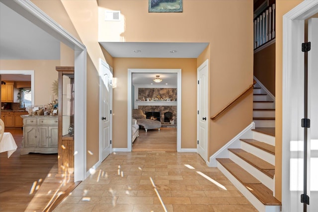 entryway with stairs, a fireplace, visible vents, and baseboards