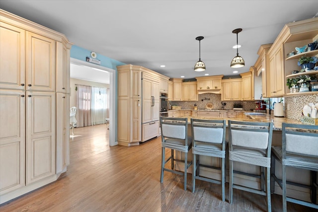 kitchen with open shelves, light wood-type flooring, a kitchen breakfast bar, and a peninsula