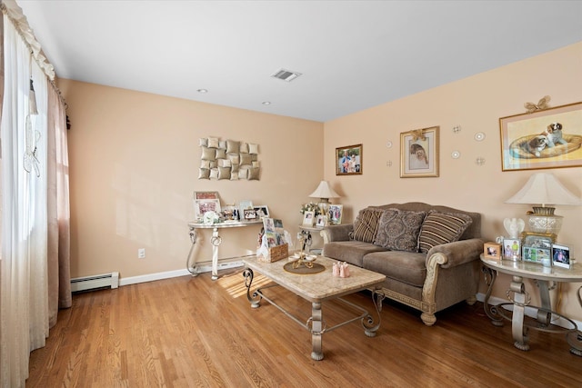 living room featuring a baseboard heating unit, wood finished floors, visible vents, and baseboards