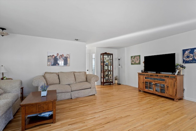 living area featuring visible vents, baseboards, and wood finished floors