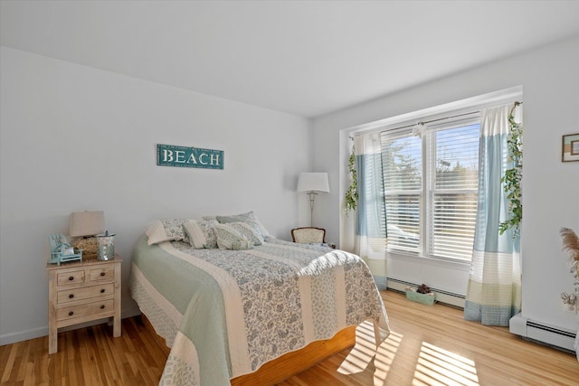 bedroom featuring wood finished floors and baseboard heating