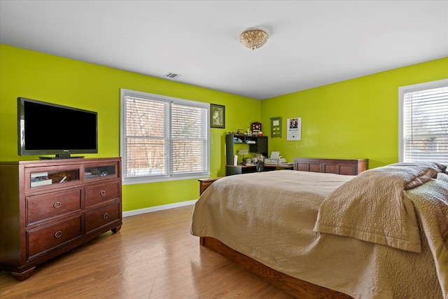 bedroom with wood finished floors, visible vents, and baseboards