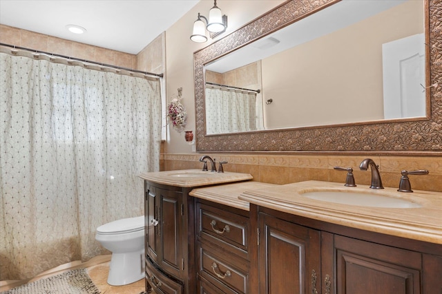 bathroom with a sink, a wainscoted wall, toilet, and double vanity