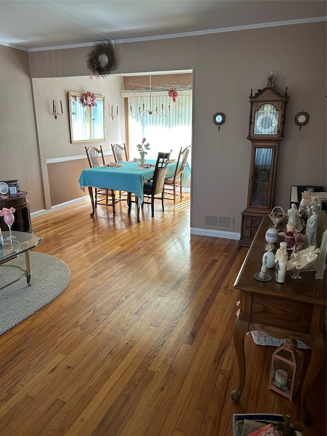 dining room featuring crown molding, baseboards, visible vents, and wood-type flooring