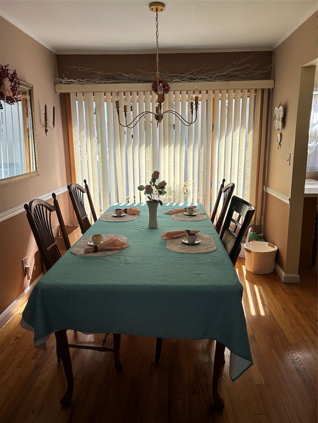 dining area with wood finished floors, baseboards, a chandelier, and ornamental molding