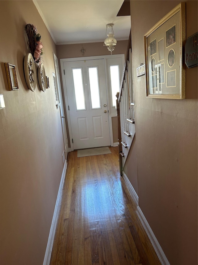 entryway with baseboards, hardwood / wood-style floors, stairs, and crown molding