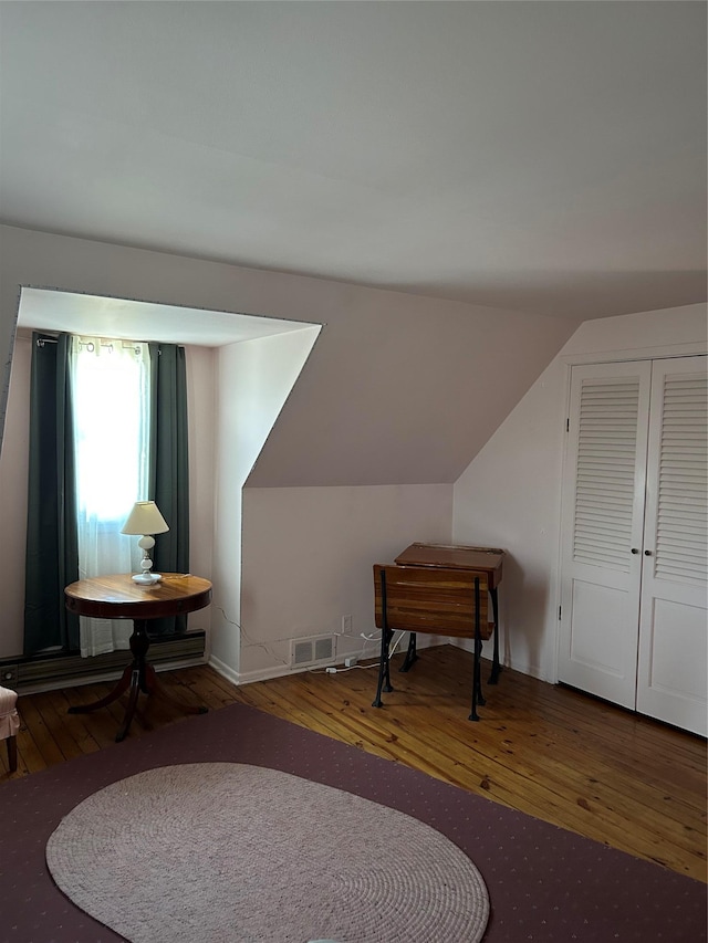 bedroom with hardwood / wood-style floors, vaulted ceiling, and visible vents