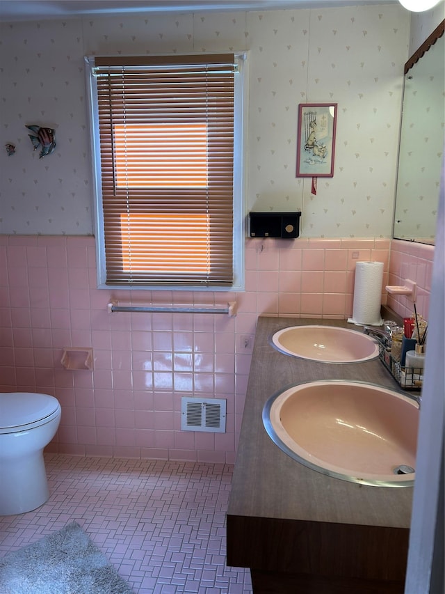 bathroom featuring a sink, visible vents, and wallpapered walls