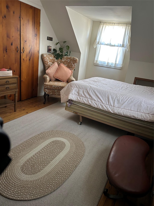 bedroom with lofted ceiling and wood finished floors