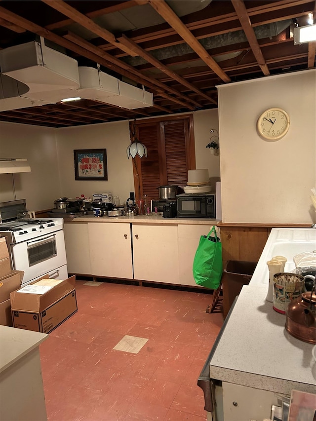 kitchen with light floors, light countertops, white gas range oven, black microwave, and white cabinetry