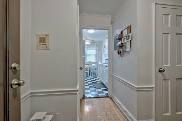 hallway with light wood-style flooring and ornamental molding