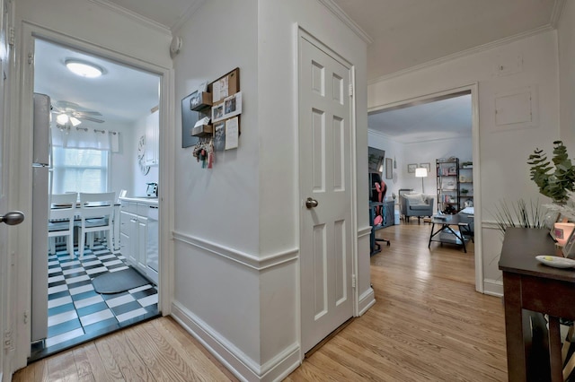 hall with crown molding, light wood-style flooring, and baseboards