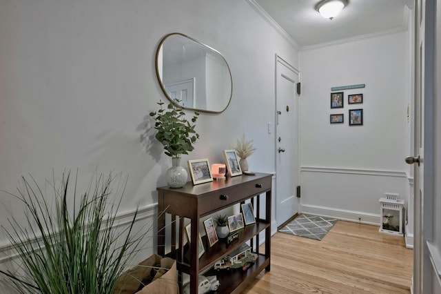 foyer featuring baseboards, crown molding, and light wood-style floors