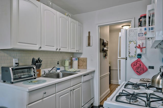 kitchen with a sink, white appliances, white cabinets, a toaster, and decorative backsplash