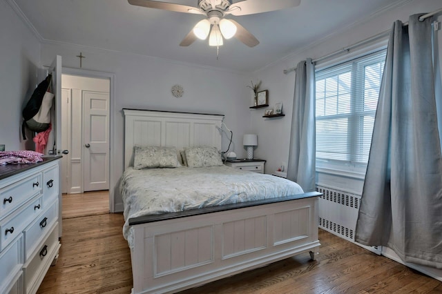 bedroom featuring crown molding, radiator heating unit, ceiling fan, and wood finished floors