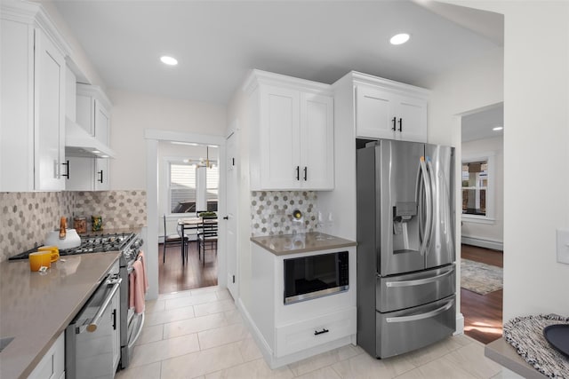 kitchen featuring backsplash, baseboard heating, recessed lighting, stainless steel appliances, and white cabinetry