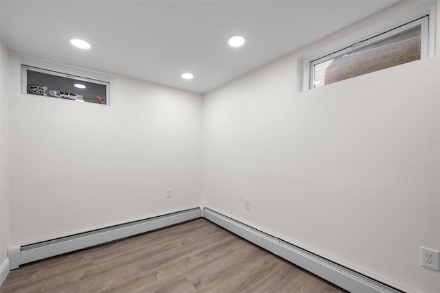 below grade area with recessed lighting, a baseboard heating unit, and wood finished floors