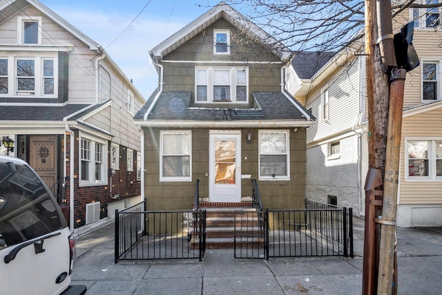 view of front facade with a gate, a fenced front yard, roof with shingles, and entry steps