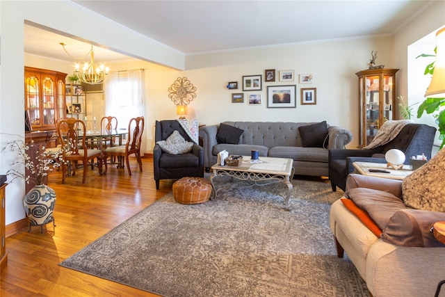 living room with a chandelier, ornamental molding, baseboards, and wood finished floors