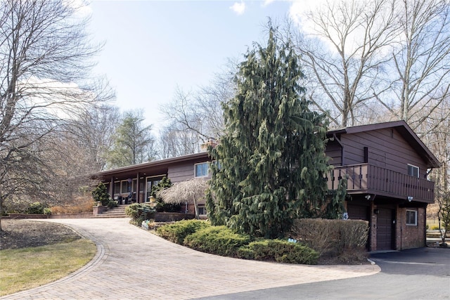 view of front of home with aphalt driveway, brick siding, covered porch, and an attached garage