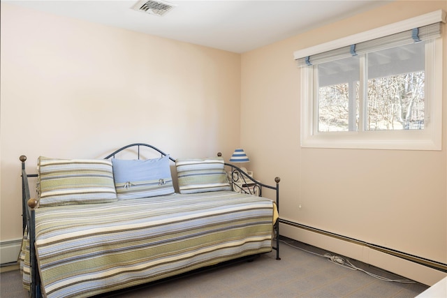 bedroom with a baseboard heating unit, visible vents, and carpet flooring