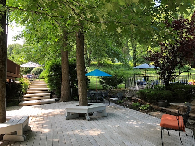 wooden terrace with stairs, outdoor dining area, and fence