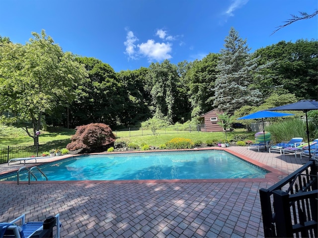 view of pool with a fenced in pool, fence, a yard, an outdoor structure, and a patio