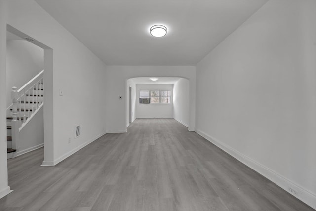 interior space featuring visible vents, arched walkways, baseboards, and wood finished floors