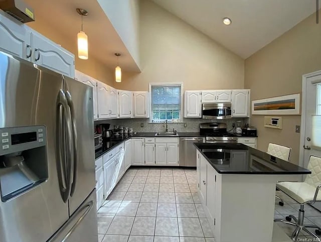 kitchen with dark countertops, backsplash, light tile patterned floors, appliances with stainless steel finishes, and white cabinetry