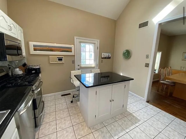 kitchen featuring visible vents, lofted ceiling, white cabinets, appliances with stainless steel finishes, and dark countertops