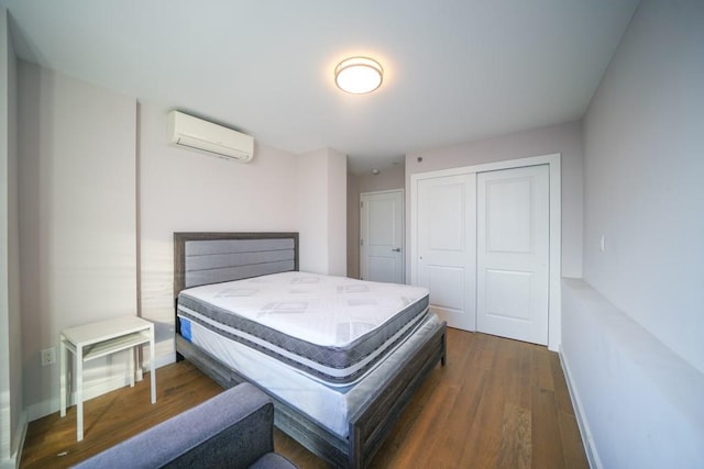 bedroom featuring a closet, baseboards, wood finished floors, and a wall mounted AC