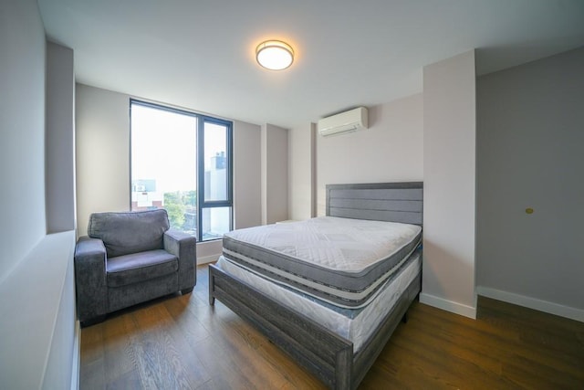 bedroom with baseboards, wood finished floors, and a wall unit AC